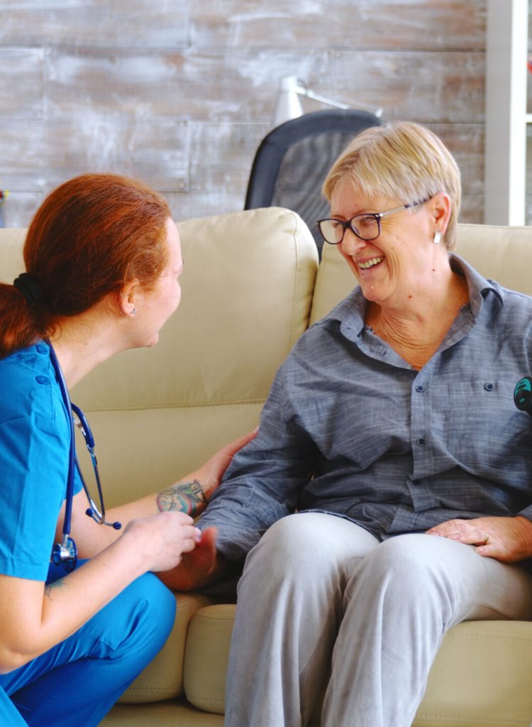 Female nurse talking with old woman with alzheimer in nursing home